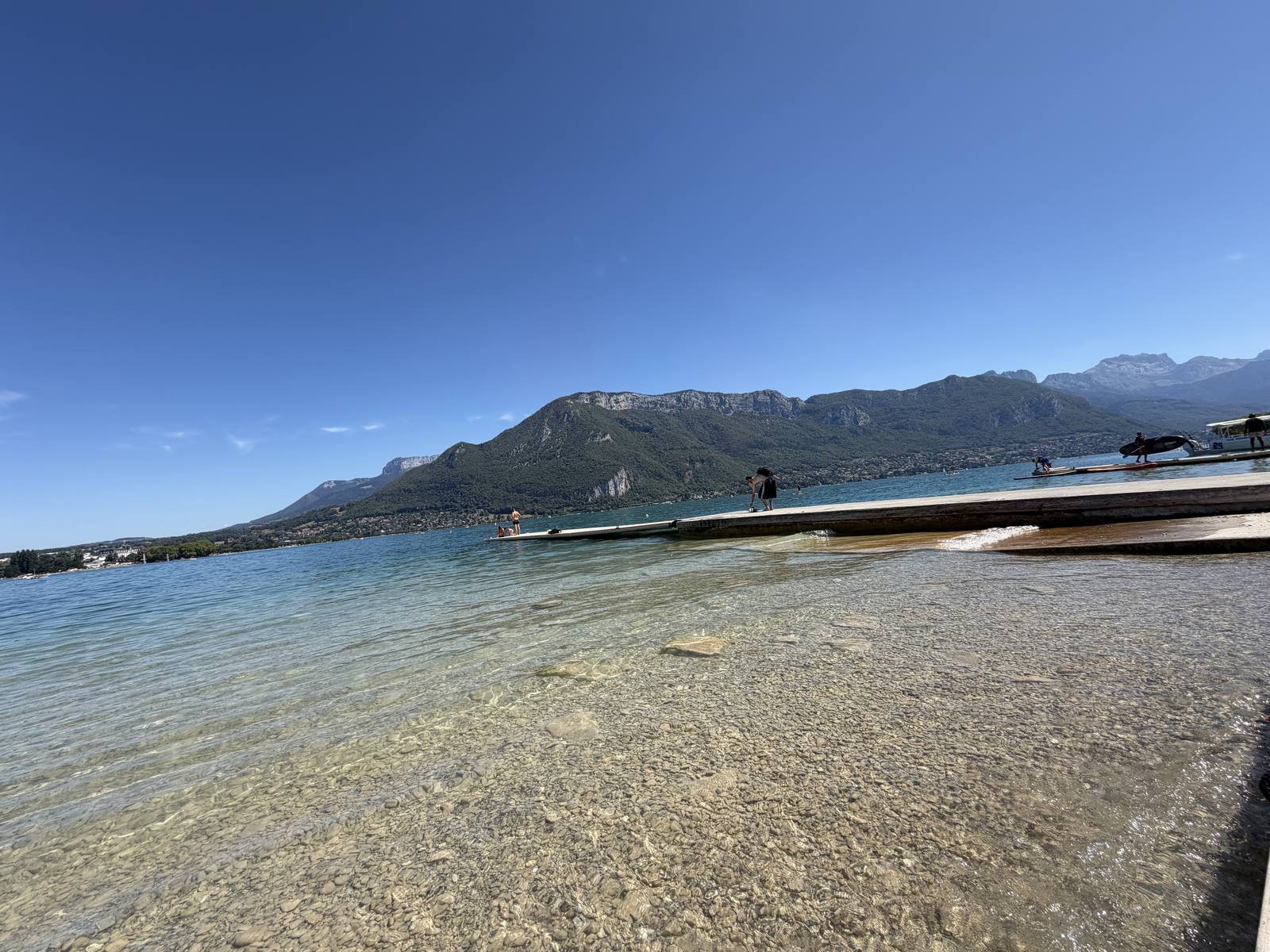 Wooden pontoon and transparent water on Lake Annecy with the Bauges massif behind